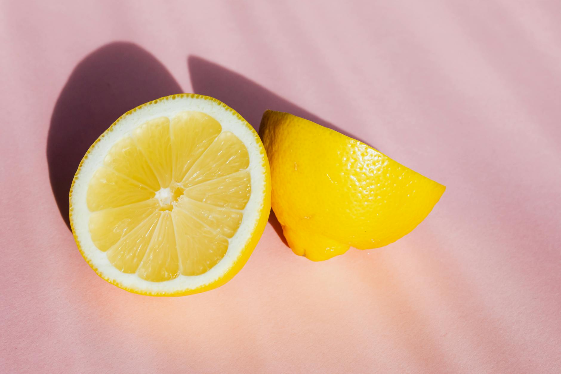 Fresh lemons on a pink background in natural sunlight, symbolizing hormonal awakening and renewal