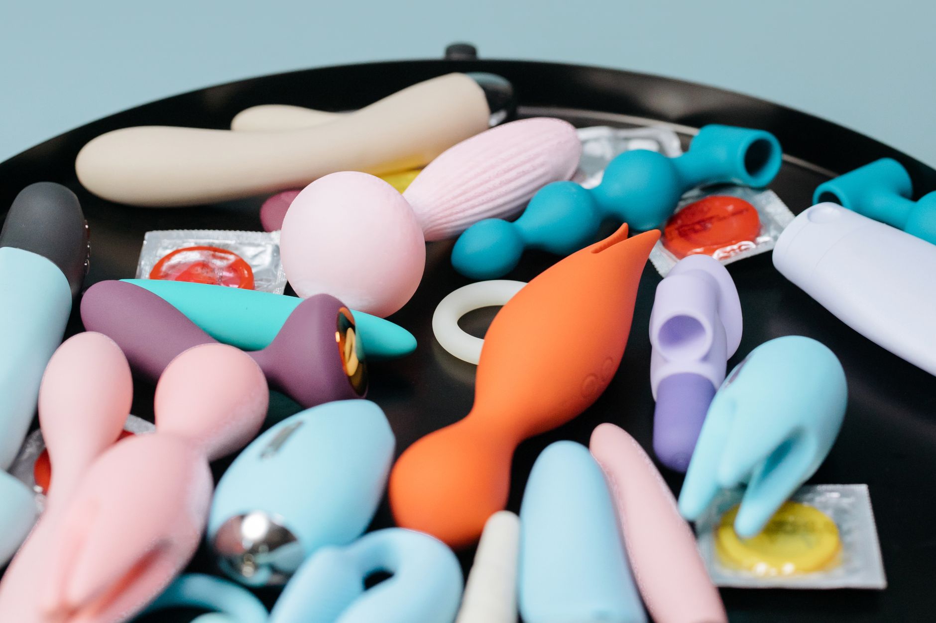 A teal clitoral vibrator on smooth white silk fabric
