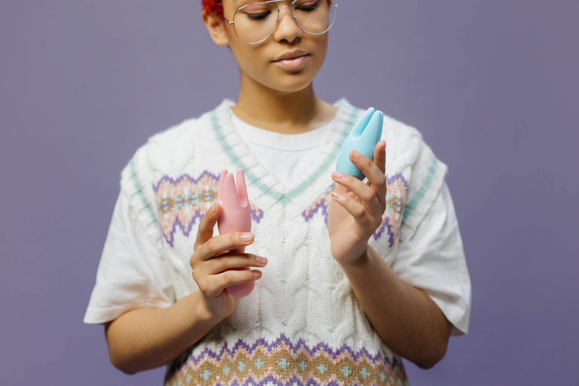 Woman holding colorful silicone vibrators in thoughtful pose